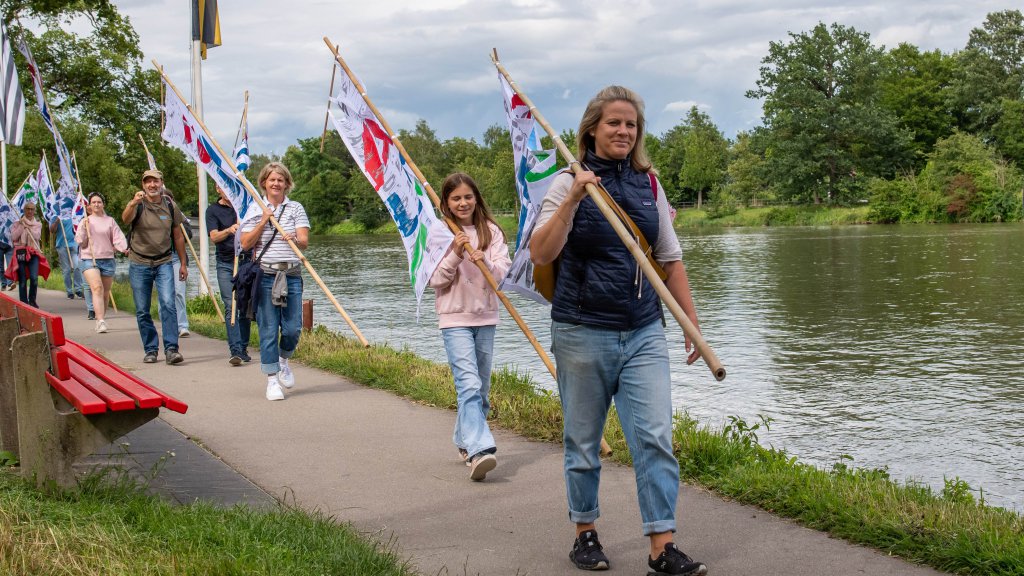 Thomas Kilb People with flags marching along a river