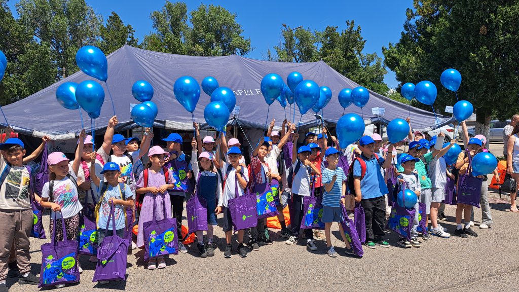 Children holding blue balloons and posing for a photo under a tent 