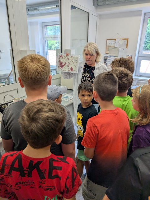 Children stand around a woman holding up a paper