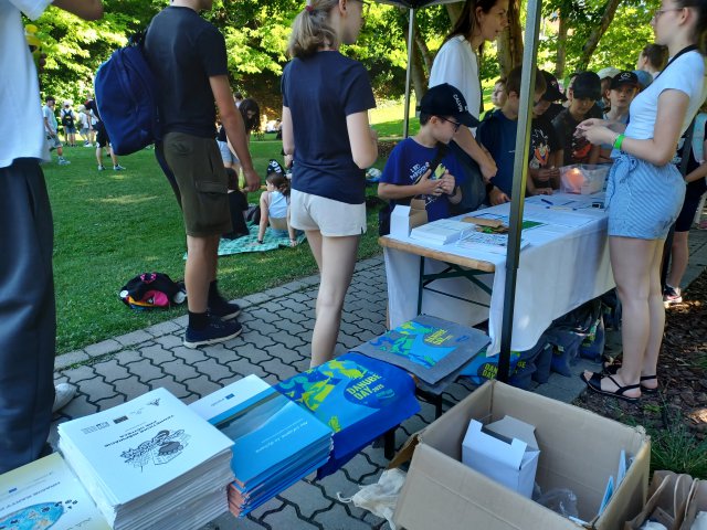 People stand under a tent with Danube Day items. 