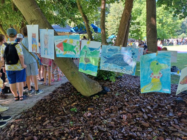 Artwork from children hangs on a line outside.