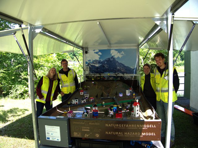 Volunteers standing under tent outside. 