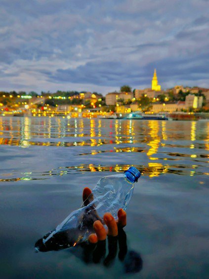 A hand offers a symbol of hope, pulling plastic waste out of the Danube River. 