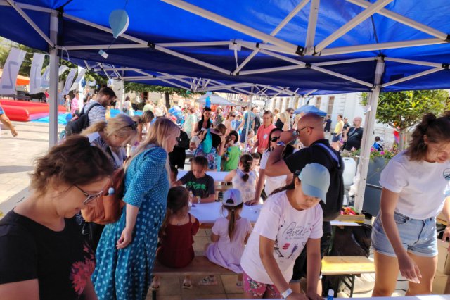Adults and children participating in activities under a tent 